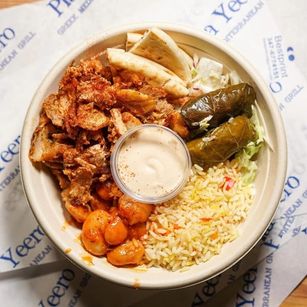 A Pita Yeero bowl with chicken, rice, pita, stuffed grape leaves, and giant beans.