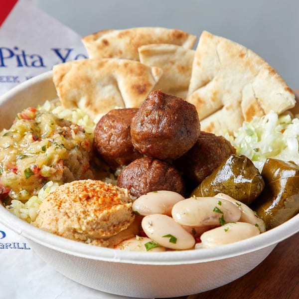 A Pita Yeero bowl filled with falafel, hummus, rice, pita bread, and stuffed grape leaves.